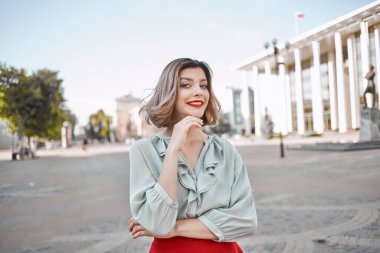 Kırmızı etekli neşeli güzel kadın dışarıda yürüyor.