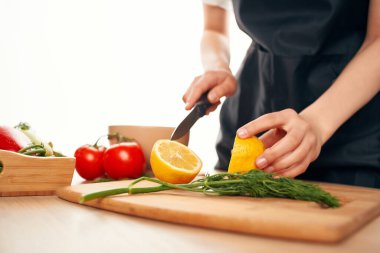 Bıçaklı mutfak malzemeleriyle tahtada limon dilimlemek.