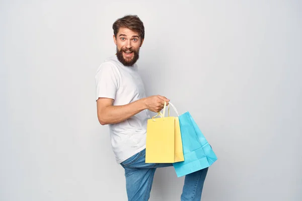 Ein Mann im weißen T-Shirt mit Paketen in der Hand spaziert durch den Unterhaltungsstil — Stockfoto