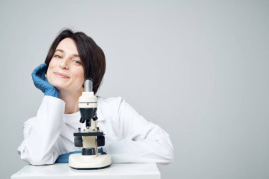 Doktor laboratuvar asistanı mikroskop araştırma masasında gülümsüyor