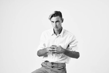 Beyaz gömlekli ve pantolonlu yakışıklı adam stüdyo tarzı modern poz veriyor.