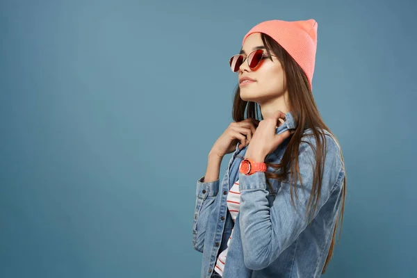 Vrouw in roze hoed zonnebril denim jas hipster blauwe achtergrond — Stockfoto