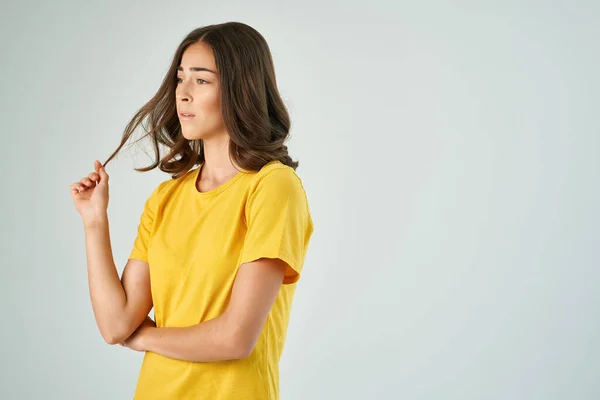 Ładna brunetka gospodarstwa włosy w żółtym t-shirt nowoczesny styl — Zdjęcie stockowe