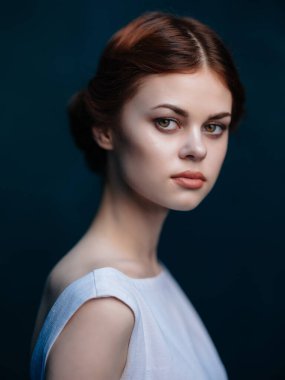 Beyaz elbiseli kızıl saçlı kadın. Çekici bir stüdyo görüntüsü var.