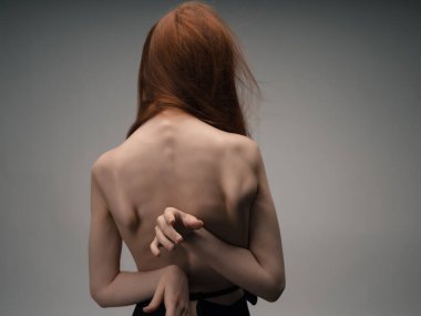 Kızıl saçlı, çıplak bir kadın, temiz cilt stüdyosuna poz veriyor.