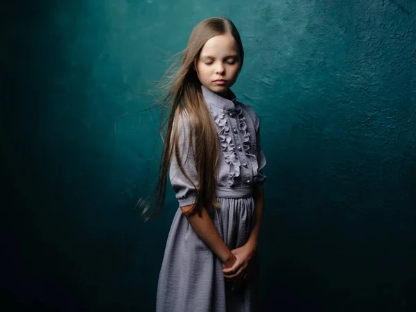 Menina com cabelos longos em um vestido posando fundo verde olhar triste — Fotografia de Stock