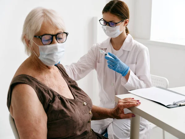 Infermiera che somministra a una donna anziana un trattamento con passaporto per iniezione covid-19 — Foto Stock