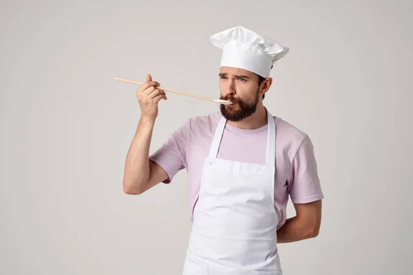 Chef profissional em uniforme com uma colher em suas mãos trabalho luz fundo — Fotografia de Stock