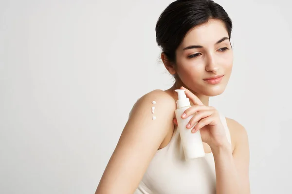 Schattig brunette in witte tank top met lotion van toepassing crème op de huid — Stockfoto