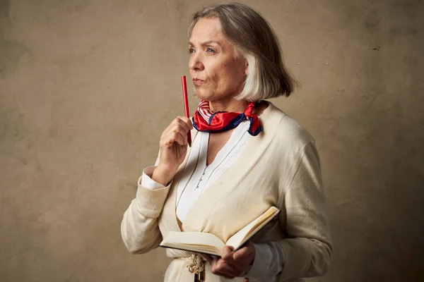 elderly woman in a dressing gown with a notebook in her hands studio