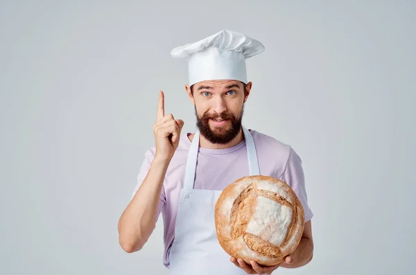 Un uomo in uniforme cuochi con il pane in mano cottura lavoro — Foto Stock