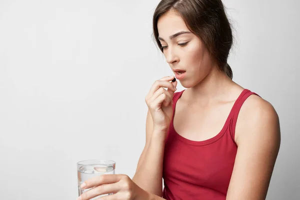 Vrouw die een pilsglas water vasthoudt en een geneesmiddelenbehandeling volgt — Stockfoto