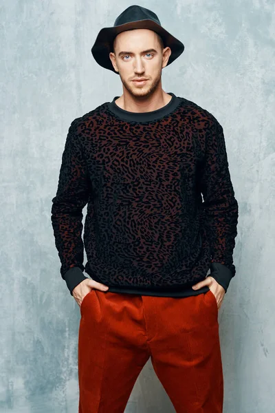 man in black sweater red pants posing studio self-confidence