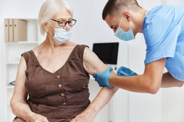 Erkek doktor, tıbbi maskelerle aşı güvencesi veriyor.