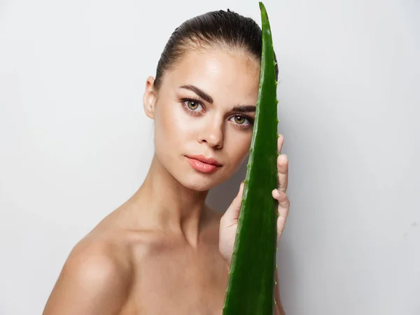 Mulher ao lado de uma folha de aloés verde em um plano composto cosmetologia pele limpa aparência natural — Fotografia de Stock