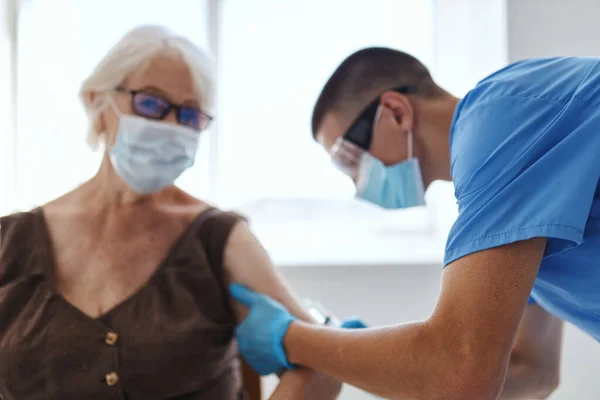 Man läkare som ger en injektion till en äldre kvinna patient covid pass — Stockfoto
