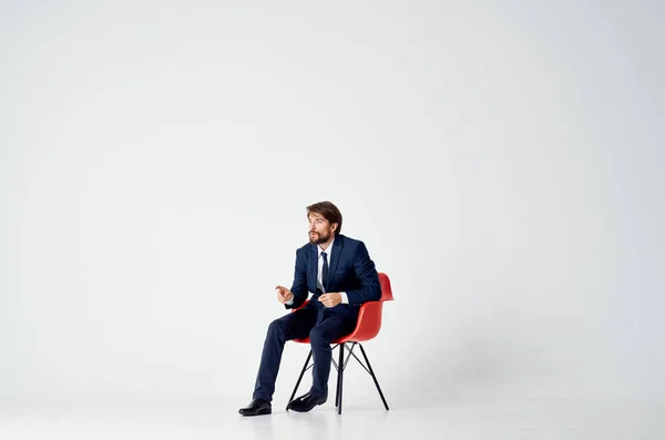 赤い椅子に座ってスーツを着たビジネスマンが — ストック写真
