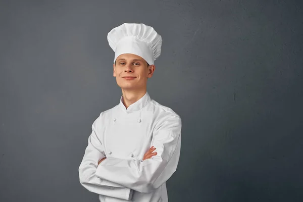 Chef professionista con espressione seria si tiene per mano di fronte a lui sfondo scuro — Foto Stock