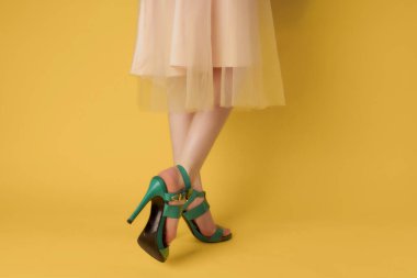 Kadın bacakları aşamalı yeşil ayakkabılar yaz tarzı sarı arka plan