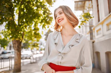 Sevimli sarışın dışarıda yürüyor, duygusal el hareketi yapıyor.