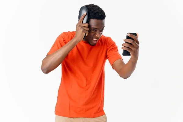 Um homem de aparência africana penteando a cabeça com um telefone — Fotografia de Stock