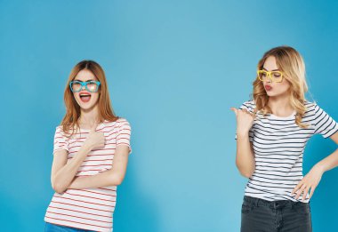 Çizgili tişörtlü iki tatlı sarışın dostluk masmavi arka plan