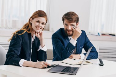 Erkek ve kadın yöneticiler dizüstü bilgisayar profesyonelleri teknolojisinin önünde masada oturuyorlar.