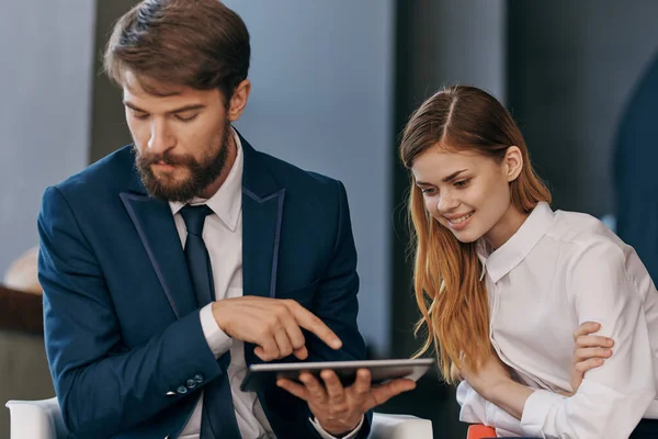 Hombre y mujer en trajes de negocios comunicarse con los funcionarios de la tableta de trabajo en equipo — Foto de Stock