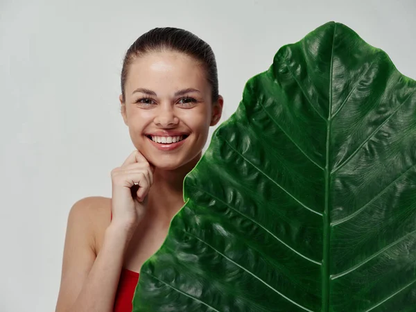 Frau mit offenem Mund und verbrennt ihre Hand in eine Faust und ein grünes Blatt einer Palme — Stockfoto