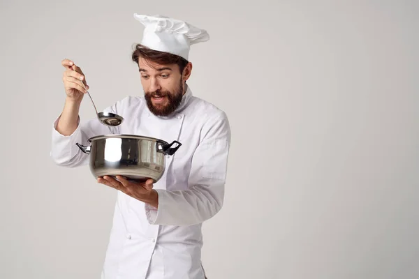 Um homem em um uniforme de cozinha com uma panela em suas mãos trabalho de serviço de cozinha — Fotografia de Stock