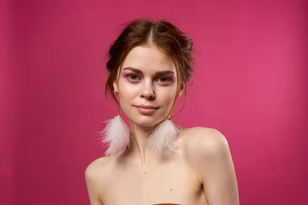 Vrouw kale schouders pluizig oorbellen heldere make-up roze achtergrond — Stockfoto