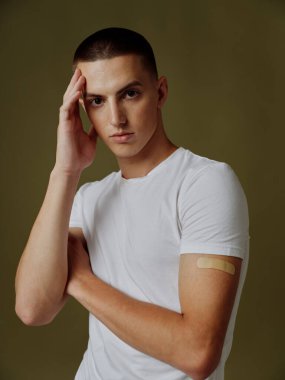 Omzunda yapıştırıcı olan bir adam elini koyu bir arka plan covid-19 pasaportuna koyar.