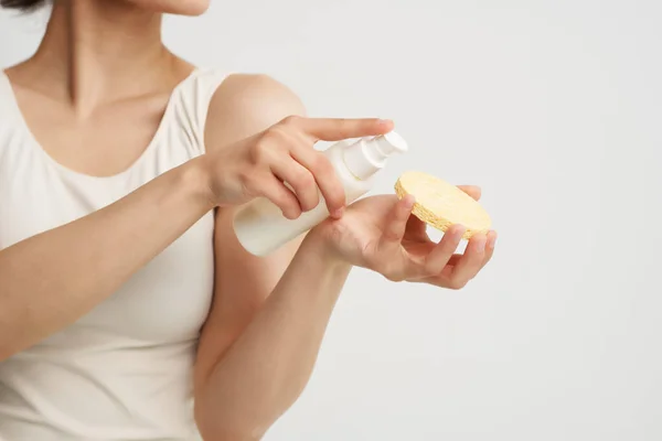 Mulher aplicando creme em uma esponja em uma camiseta branca close-up — Fotografia de Stock