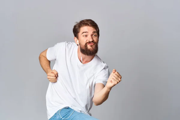 Un uomo in una t-shirt bianca gesti con le mani emozioni movimento studio luce sfondo — Foto Stock