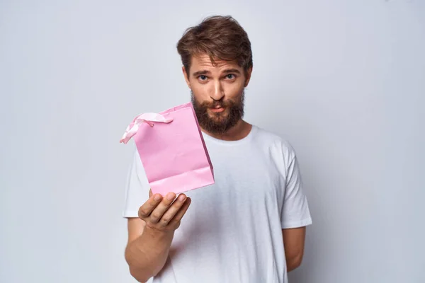 Uomo barbuto in bianco t-shirt rosa pacchetto regalo per studio donna — Foto Stock