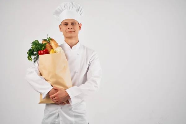 Un uomo in uniforme da chef con un pacchetto di prodotti gesticolando con la mano cucina sana — Foto Stock