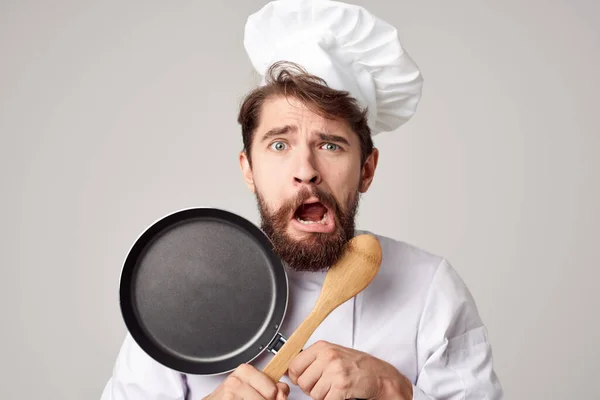 Un homme dans un uniforme de chefs une poêle à frire dans les mains travail de cuisine — Photo