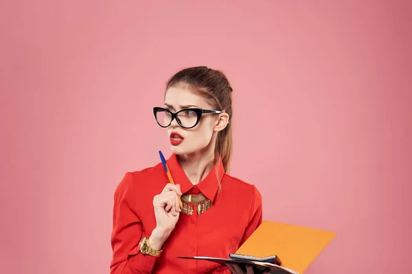 Vrouw in rood shirt en glazen documenten in handen van secretaresse roze achtergrond — Stockfoto