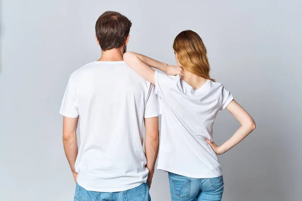 Mężczyzna i kobieta w białych t-shirtach stoją z tyłu lekka makieta tła — Zdjęcie stockowe