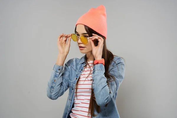 Femme en chapeau rose lunettes jaunes maison hipster fond gris — Photo