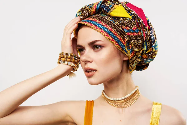 Vacker kvinna som håller hennes huvud dekoration flerfärgad turban mode ljus bakgrund — Stockfoto