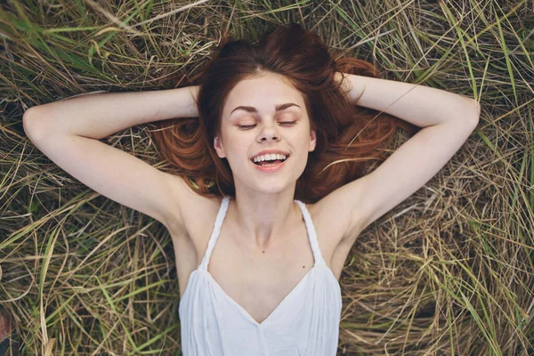 Žena v bílých šatech leží na trávě pole příroda zábava — Stock fotografie