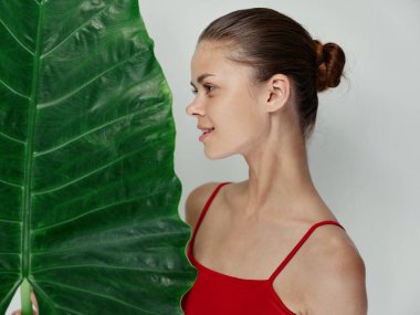 Kırmızı mayo giymiş bir kadın, palmiye yaprağı görünümlü aydınlık arka plan