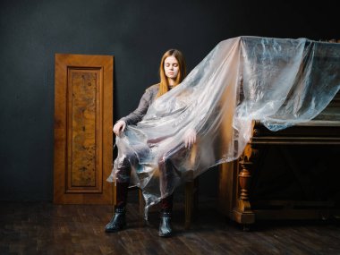 Kadın piyanonun yanında oturuyor. Sandalyenin üstünde. Romantizm enstrümanı.