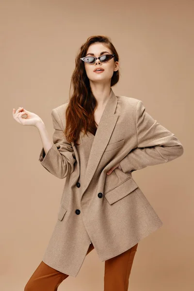 베이지 코트를 입고 갈색 바지 안경을 쓴 매력적 인 여성 얼굴 화장 모델 — 스톡 사진