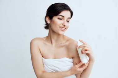 Havlu giymiş esmer, çıplak omuzlu, cilt kremi sürmüş.