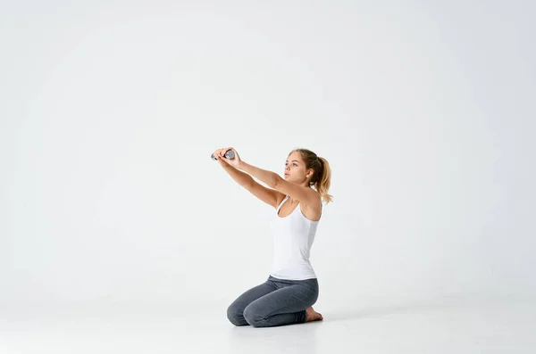 Kobieta siedzi boso na podłodze hantle w rękach ćwiczenia mięśni trening — Zdjęcie stockowe