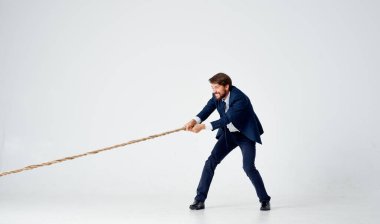 Takım elbiseli bir iş adamı halat stüdyosunun ışık arka planını çeker.