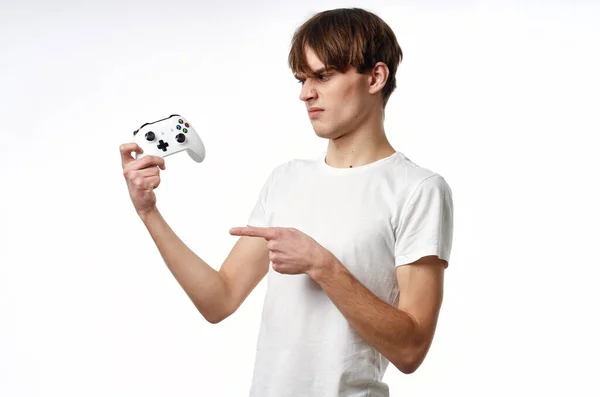 Jonge kerel in een wit t-shirt Joystick in de handen van het spel emoties licht achtergrond — Stockfoto