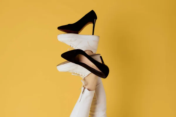 Damskie czarne buty na odwrócone nogi żółte tło — Zdjęcie stockowe